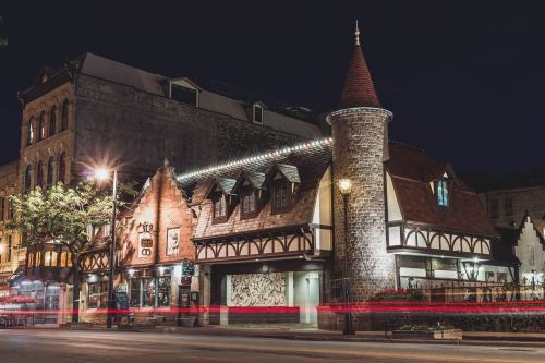 A charming, illuminated building with a turret, featuring a mix of stone and wood architecture at night.