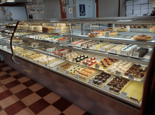 A display case filled with a variety of colorful cakes, pastries, and desserts in a bakery.