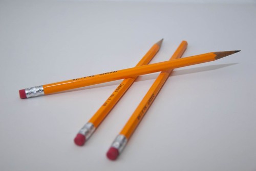 Three yellow pencils with pink erasers arranged on a white surface.