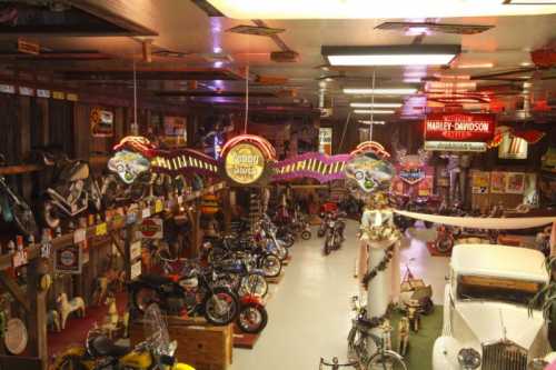 A vintage motorcycle museum filled with various bikes, neon signs, and memorabilia in a rustic setting.