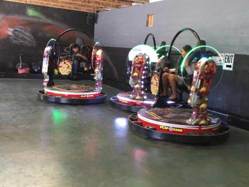 Two colorful arcade rides with glowing lights, occupied by children, set in a fun indoor amusement area.