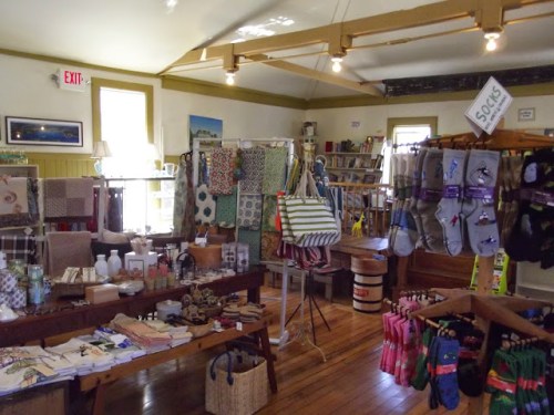 A cozy shop interior filled with colorful textiles, home goods, and accessories displayed on tables and shelves.