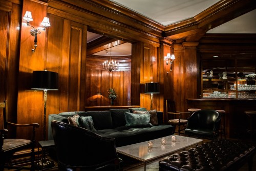 Cozy lounge with dark wood paneling, plush seating, and soft lighting, creating an inviting atmosphere.