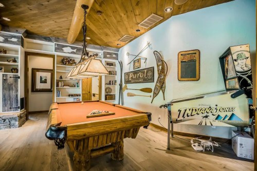 A rustic game room featuring a wooden pool table, vintage decor, and a cozy atmosphere with warm lighting.