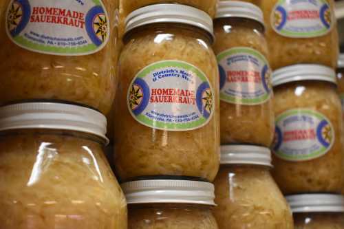 Jars of homemade sauerkraut stacked on a shelf, each labeled with a colorful sticker.