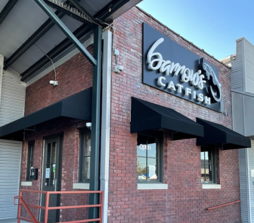 Exterior of a brick building with a sign reading "Gambro's Catfish" and black awnings, indicating it's open.