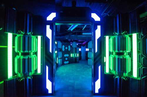 A futuristic hallway with glowing green and blue lights, featuring high-tech walls and a dark, sci-fi atmosphere.