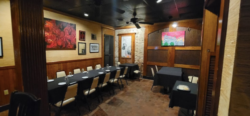 A cozy restaurant interior with a long table set for dining, surrounded by artwork and wooden accents.