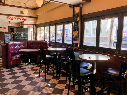Interior of a restaurant with red booths, tables, and large windows, featuring a checkered floor and warm lighting.