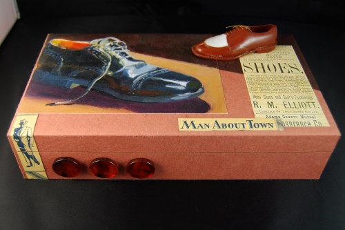 A decorative shoe box featuring a painted shoe, vintage shoe advertisements, and three red buttons on the side.