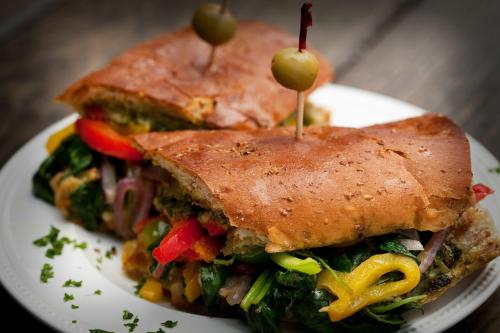 A close-up of a sandwich filled with colorful vegetables, topped with two olives on toothpicks, served on a plate.