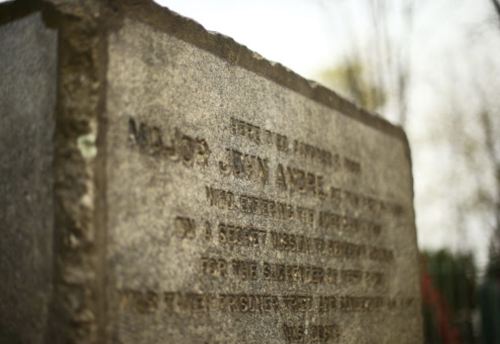 A weathered gravestone with an inscription honoring Major John Amble, surrounded by trees.
