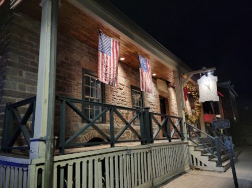 Historic building at night, featuring American and Maryland flags, with a welcoming porch and decorative wreath.