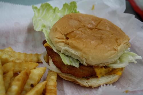 A crispy chicken sandwich with lettuce and cheese, served with crinkle-cut fries on the side.