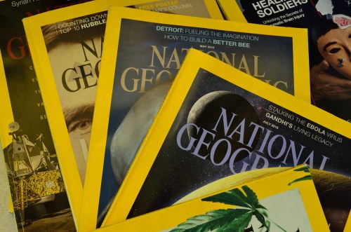 A stack of National Geographic magazines with yellow borders, featuring various cover topics and dates.