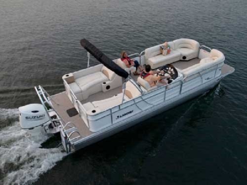 A pontoon boat with two people relaxing on it, cruising on calm water.