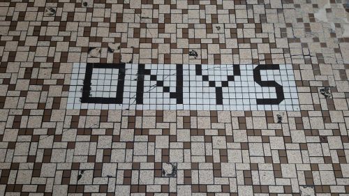 Mosaic tile floor with the word "ONYS" prominently displayed in black tiles on a light background.