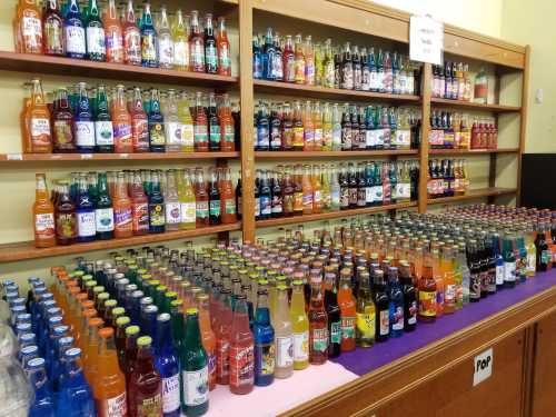 A colorful display of various soda bottles arranged on shelves and tables in a store.