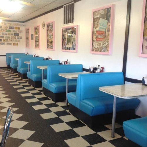 Retro diner interior with blue booths, checkered floor, and vintage decor on the walls.