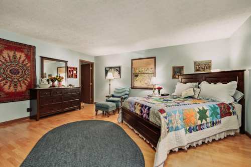 Cozy bedroom featuring a quilted bed, wooden furniture, and decorative wall art in soft lighting.