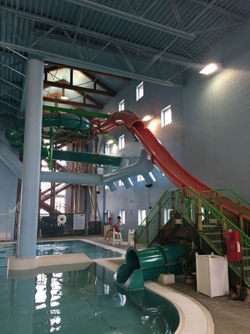 Indoor water park featuring multiple water slides and a pool area. Brightly lit with blue walls and green accents.