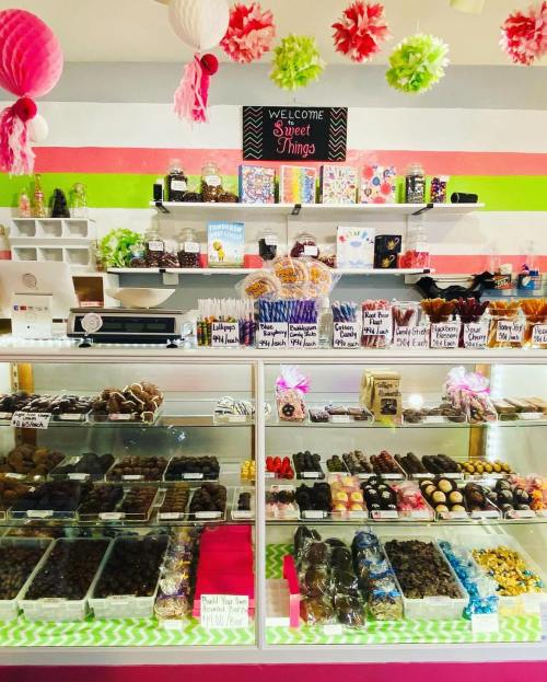 A colorful candy shop display featuring various sweets, chocolates, and treats under festive decorations.