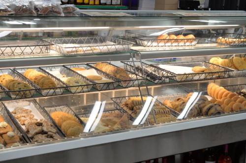 A display case filled with various baked goods, including cookies, pastries, and bread, neatly arranged on trays.