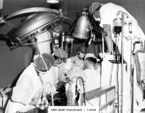 Historic black-and-white photo of surgeons performing the first heart transplant in 1964, surrounded by medical equipment.