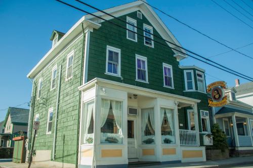 A green, two-story building with white trim and large windows, featuring a sign for a restaurant. Clear blue sky above.