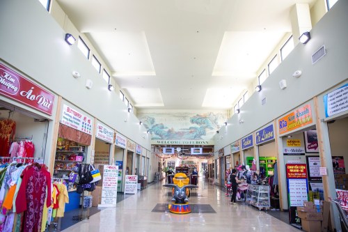 A vibrant indoor market with colorful shops lining the walls and a central play area for children.