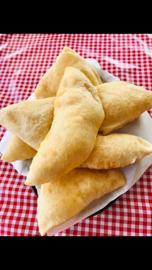 A plate of golden, crispy pastries stacked on a red and white checkered tablecloth.