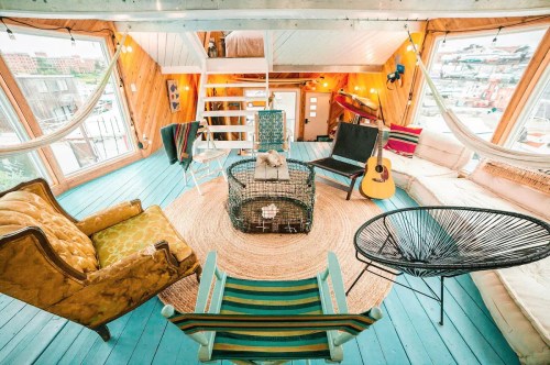 Cozy, colorful living space with eclectic furniture, a guitar, and large windows overlooking a scenic view.