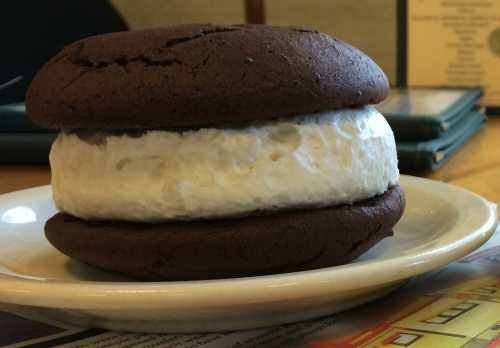 A chocolate whoopie pie with a fluffy white filling, resting on a plate.