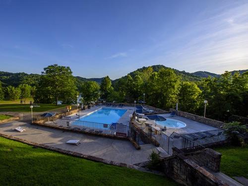 A scenic outdoor pool area surrounded by lush greenery and mountains under a clear blue sky.