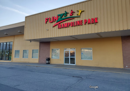 Exterior of Fun Zone Trampoline Park, featuring a colorful sign and large windows on a yellow building.