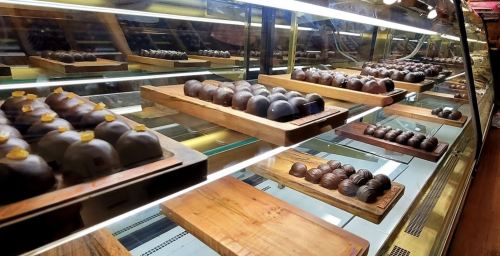 A display case filled with various chocolate confections arranged on wooden trays.