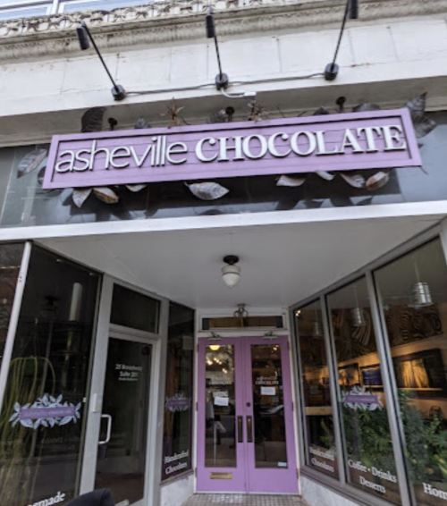Sign for Asheville Chocolate, featuring a storefront with large windows and decorative elements above the entrance.