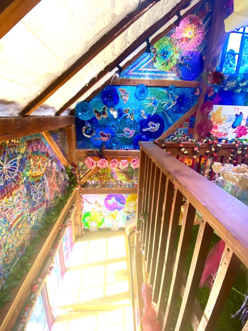 Colorful, artistic walls adorned with butterflies and flowers, viewed from a staircase in a bright, vibrant space.