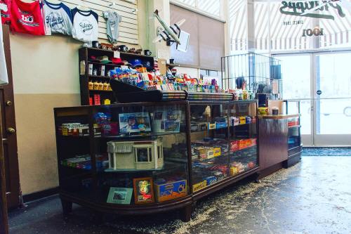 A vintage store counter filled with snacks and candy, featuring a glass display and merchandise in the background.