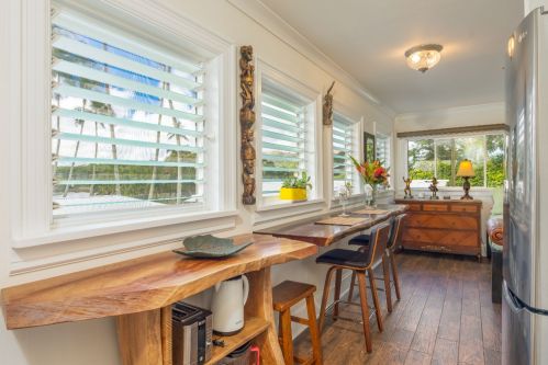 Bright kitchen with wooden accents, large windows, and a dining area featuring a table and chairs.