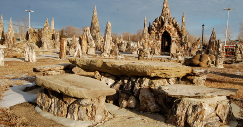 A unique outdoor landscape featuring stone sculptures and formations, with a large stone bench in the foreground.