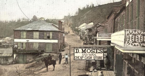 Historic street scene featuring wooden buildings, a horse, and a sign for "D. Moses and Sons Cheap Cash Store."