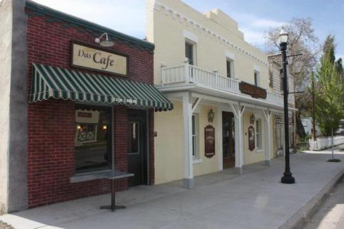 A quaint street scene featuring a cafe with a striped awning and a historic building beside it, under a clear sky.