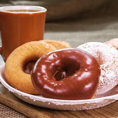 A plate of assorted donuts, including chocolate, powdered, and plain, next to a cup of coffee.