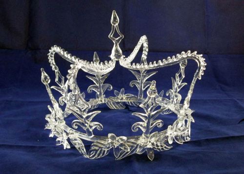 A delicate crystal crown adorned with floral designs, set against a dark blue background.