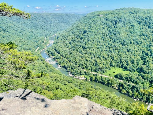 A scenic view of a winding river surrounded by lush green hills under a clear blue sky.
