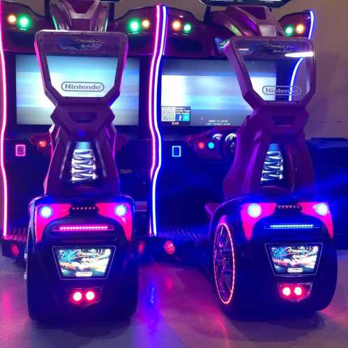 Two colorful arcade racing machines with glowing lights and screens, featuring Nintendo branding.