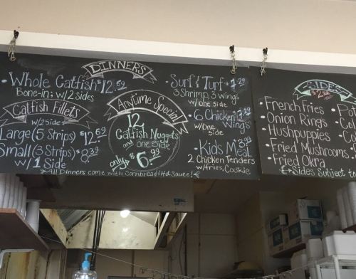 Chalkboard menu displaying dinner options, including catfish, wings, and sides, with prices listed.