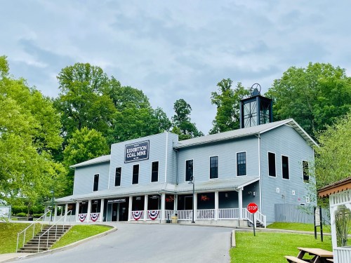 A gray building labeled "Exhibition Coal Mine" surrounded by greenery and a stop sign in the foreground.