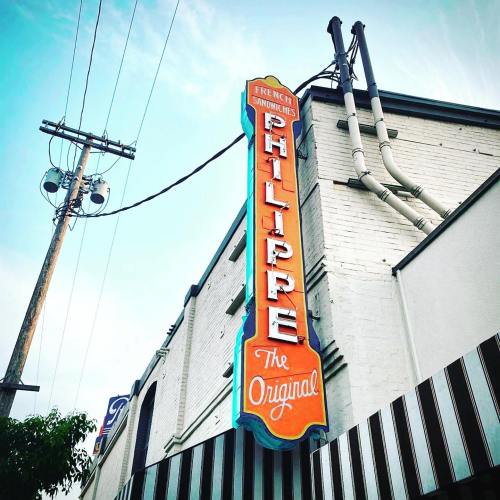 Sign for "Philippe The Original" restaurant, featuring colorful lettering and a vintage design against a clear sky.